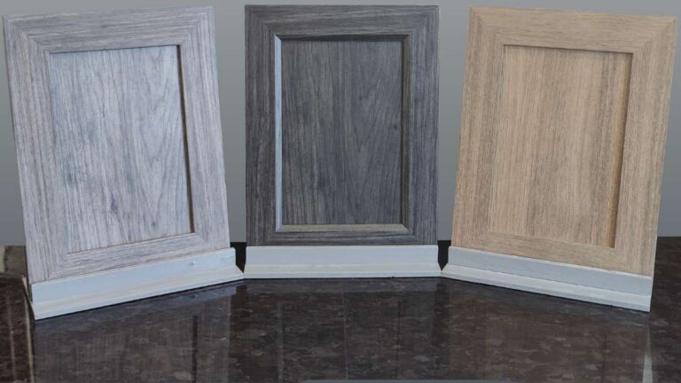 Three NEXGEN cabinet doors (one grey, one dark grey, and one brown) on a black countertop.