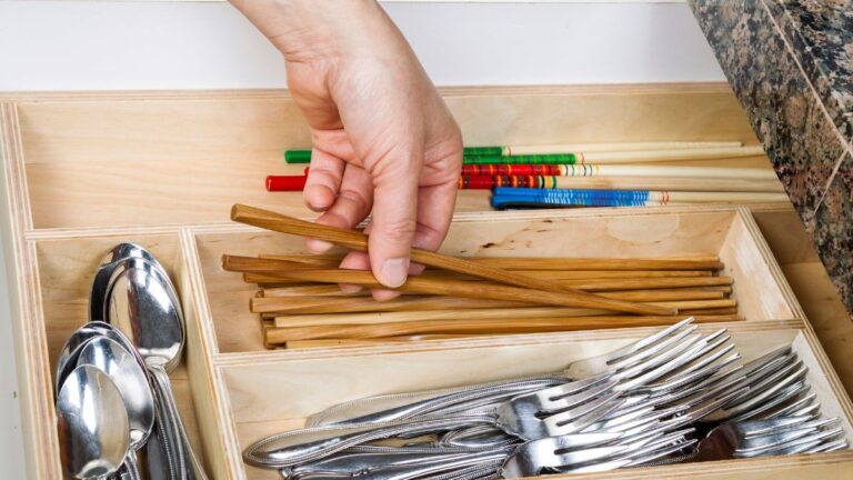A hand placing items into a drawer organizer.
