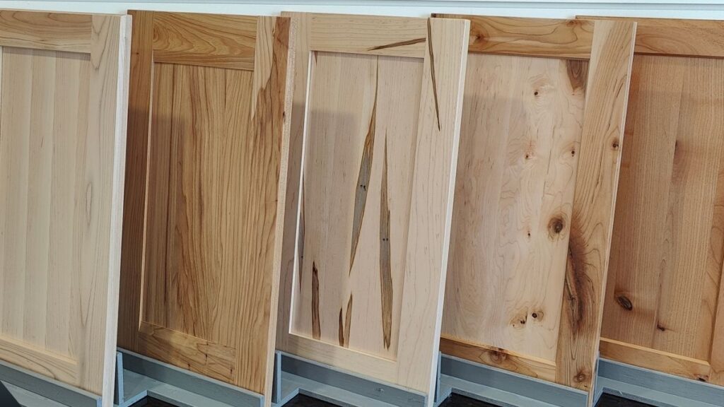 Five shaker style cabinet doors with solid wood panels in a variety of wood species.