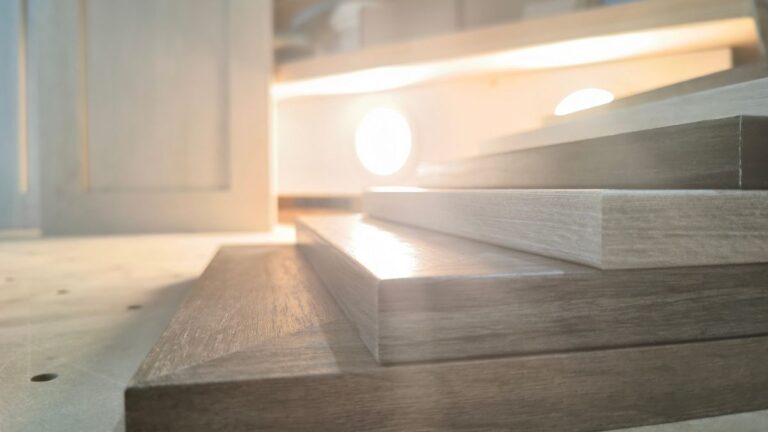 A stack of six NEXGEN cabinet doors in various colours on a pegboard table. Two more NEXGEN cabinet doors are standing upright in the background.