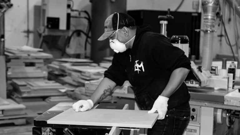 An employee applying an outside profile to a cabinet door using a router table.