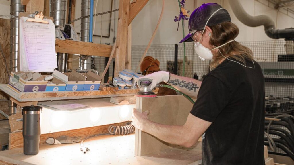 An employee sanding two cabinet doors.