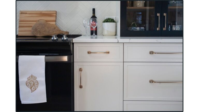 Slim shaker 1-piece MDF cabinet doors, painted white with brass handles, next to a black stove.