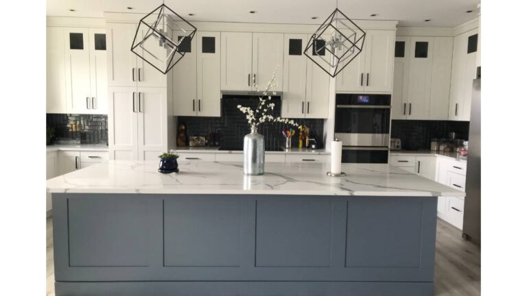 A kitchen with white painted cabinet doors around the perimeter and blue painted cabinet doors on the island.