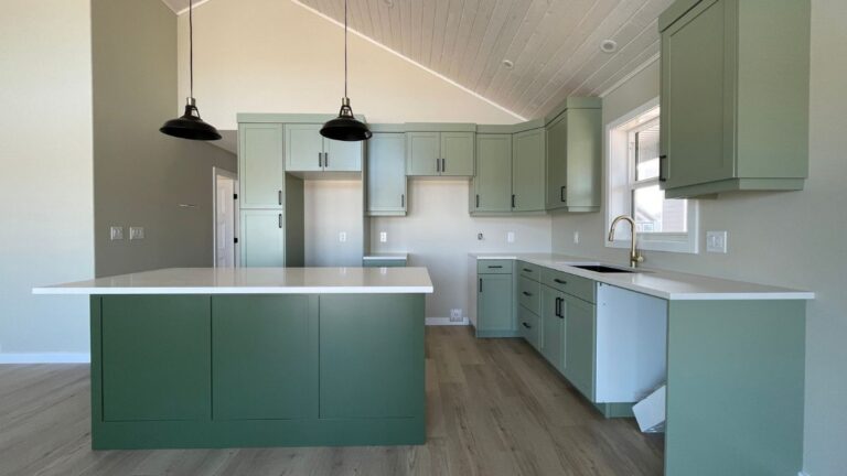 A kitchen with green painted cabinet doors, black light fixtures and handles.