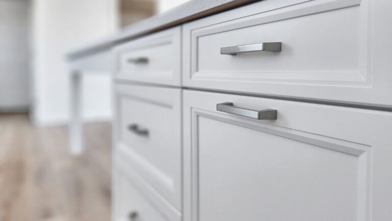 A close-up view of white painted 1-piece MDF cabinet doors with silver hardware.