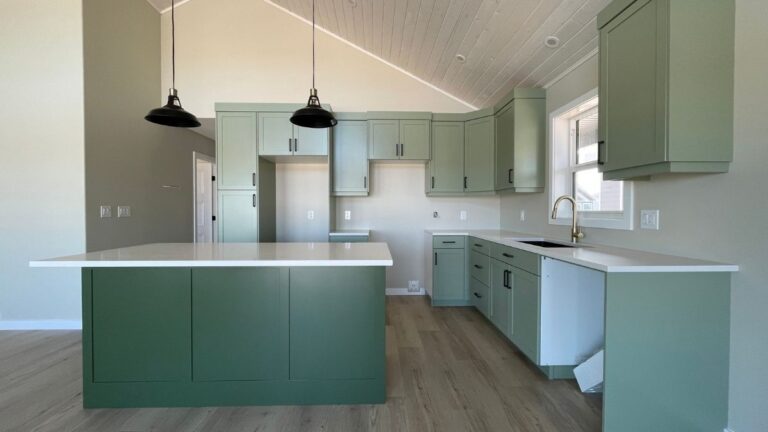 A kitchen with green painted 1-piece MDF cabinet doors and black hardware.