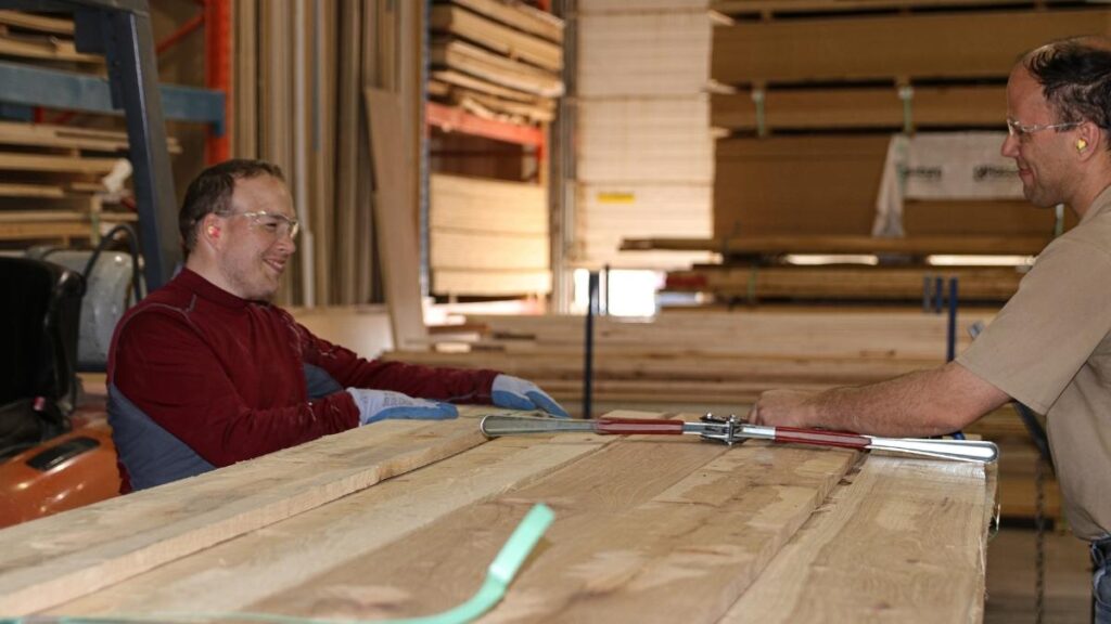 Cutting Edge stocks raw lumber for its cabinet doors. In this picture, two employees are standing next to a lift of lumber.