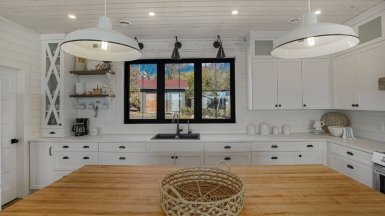 This white painted kitchen features a decorative mullion frame and glass cabinet doors with frosted glass.