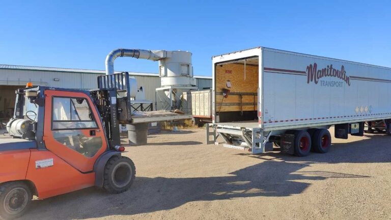 An orange forklift loading a pallet of cabinet doors into a Manitoulin semi trailer. Cutting Edge ships into Alberta using Manitoulin Transport and other companies.