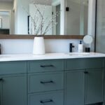 A vanity with teal 1-piece MDF slim shaker cabinet doors and black hardware.