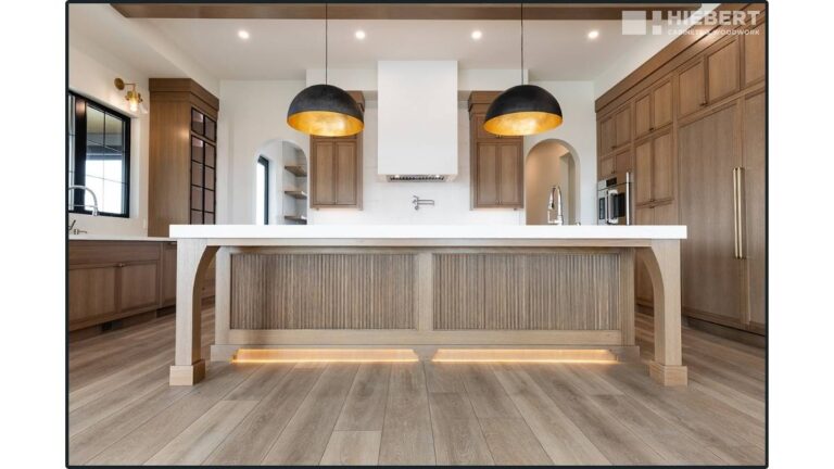 A kitchen with light-brown stained Rift Cut White Oak custom cabinet doors. Complex custom pieces, like the fluted decorative island panels, take longer to produce so you should order them in advance.