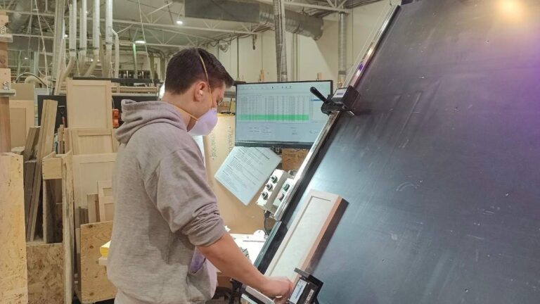 A Cutting Edge employee placing a cabinet door on the ProTable. If a cabinet door is not flush with the table, we inspect it closely for warp.