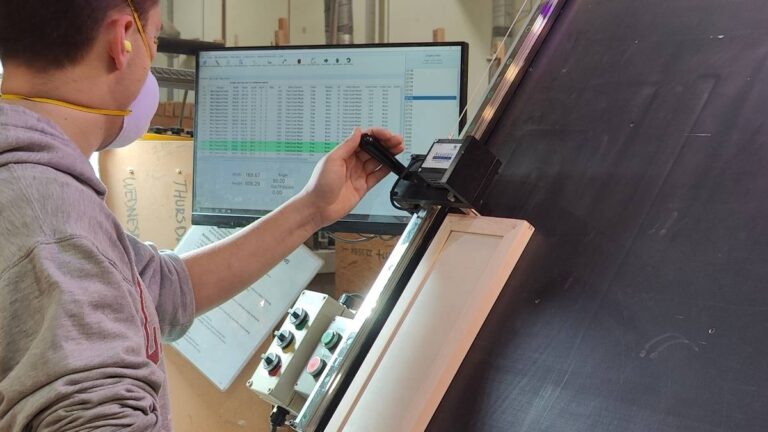 A Cutting Edge employee verifying the outside dimensions of a cabinet door.