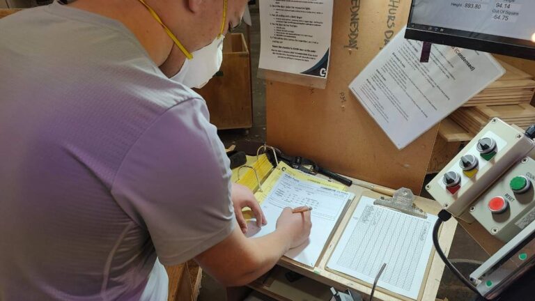 A Cutting Edge employee signing an order form. This is the final step after inspecting an order of cabinet doors.