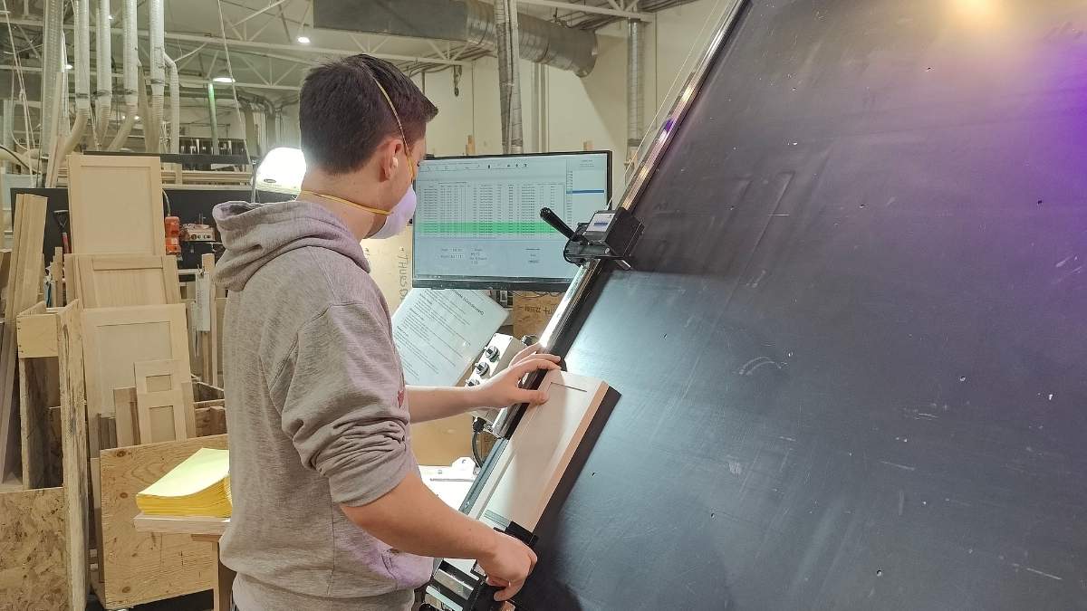 A Cutting Edge employee standing in front of a measuring table, measuring a drawer front. All of Cutting Edge's cabinet doors go through a quality inspection.