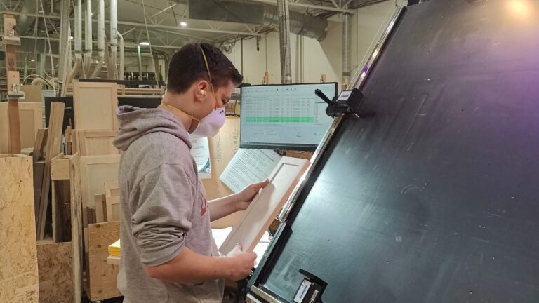 A Cutting Edge employee inspecting a cabinet door. All cabinet doors from Cutting Edge go through a quality inspection.