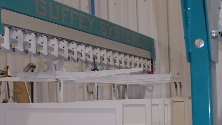 Finished cabinet doors hanging on a rack provided by Guffey Systems. Spraying cabinet doors vertically takes less time than the traditional flat method.