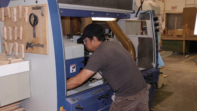 An employee reaching into a machine to perform maintenance. Frequent maintenance reduces the possibility of delays for your NEXGEN cabinet doors.