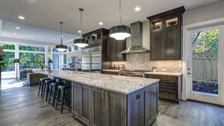 A kitchen featuring dark-grey stained shaker-style cabinet doors, a quartz countertop, and a grey tile backsplash. Spray stain finishes provide consistent results when done correctly.