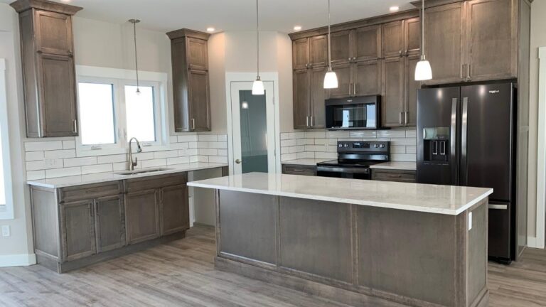 A kitchen with grey stained hard Maple cabinet doors, white countertops, and a white subway tile backsplash.