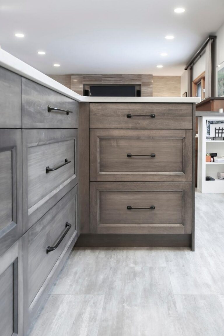 An island with grey-stained hard Maple drawer fronts and black hardware.