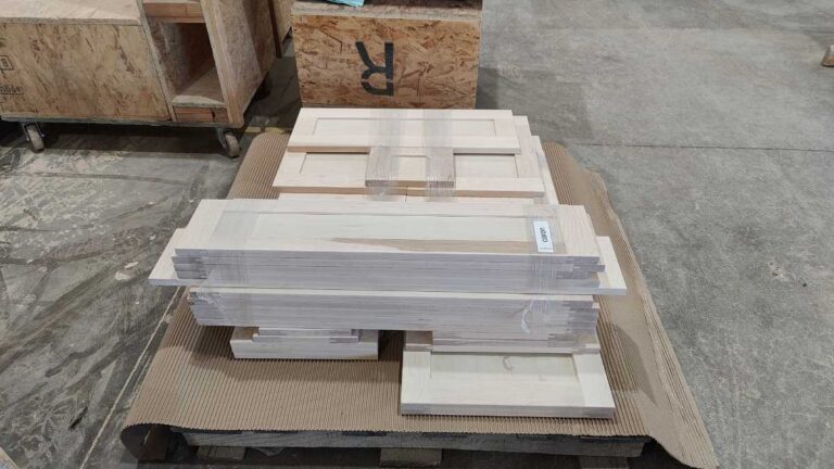 Cabinet doors bundled in groups of five and stacked on a pallet.