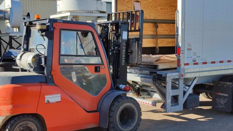 An orange forklift loading a pallet into a white and red semi trailer. Cutting Edge ships cabinet doors to Saskatoon via Manitoulin Transport.