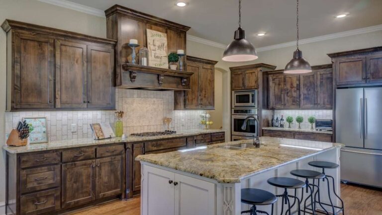 A farmhouse kitchen with dark-brown stained cabinet doors and drawer fronts and a painted island. Solid wood slab cabinet doors, like the drawer fronts, provide a warm feel to the kitchen.