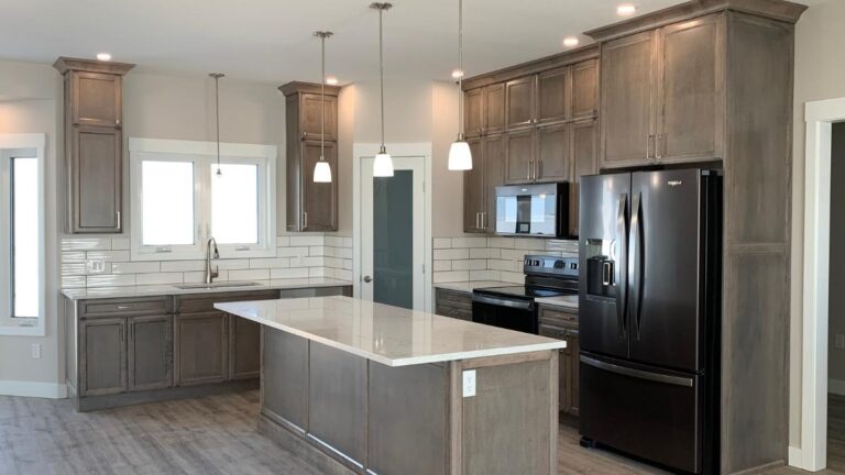 A kitchen with grey-stained hard Maple cabinet doors, silver hardware, and black appliances.