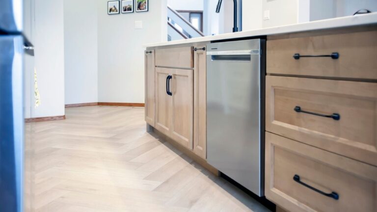 A kitchen with light-brown stained cabinet doors and drawer fronts and black hardware.