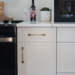 A kitchen with white painted slim shaker cabinet doors and brass hardware. You can order three types of slim shaker cabinet doors.