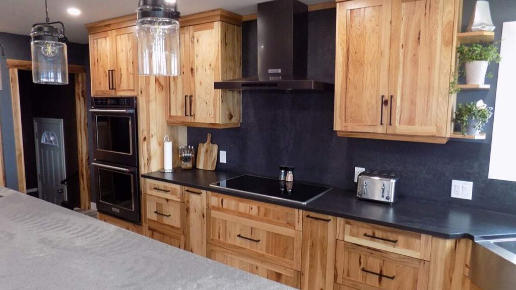 A kitchen with knotty cabinet doors and black hardware.